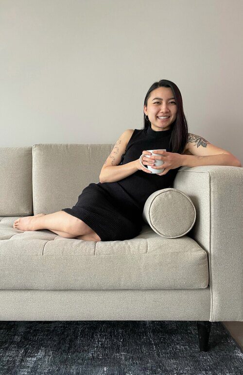 dr. suki hon naturopathic doctor toronto headshot side sitting on couch holding mug against neutral background (small)